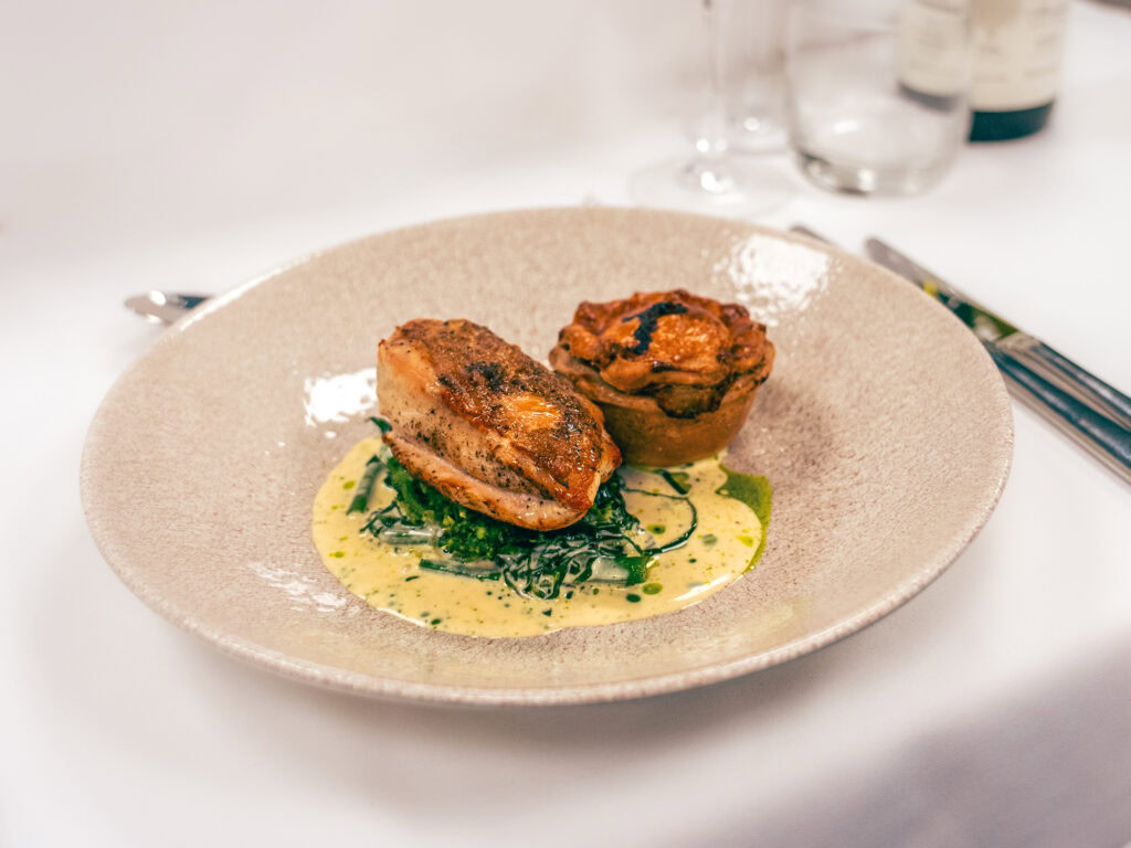 Succulent roasted pork fillet with a mushroom stuffed potato and green vegetable accompaniment, served with a creamy sauce.