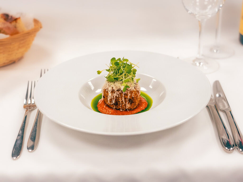 Delicious gourmet dish with microgreens, sauce, and vibrant garnishes on fine white plate.