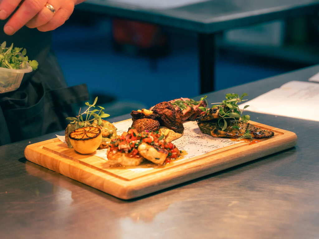 Succulent grilled meat and vibrant vegetable dishes served on a wooden platter for an upscale dining experience.