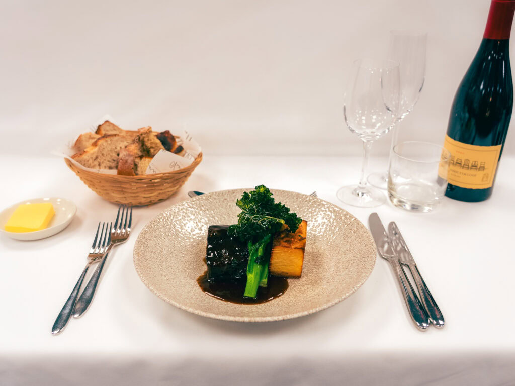 Elegant plated main course with vegetables and sauce, served on a textured beige plate.