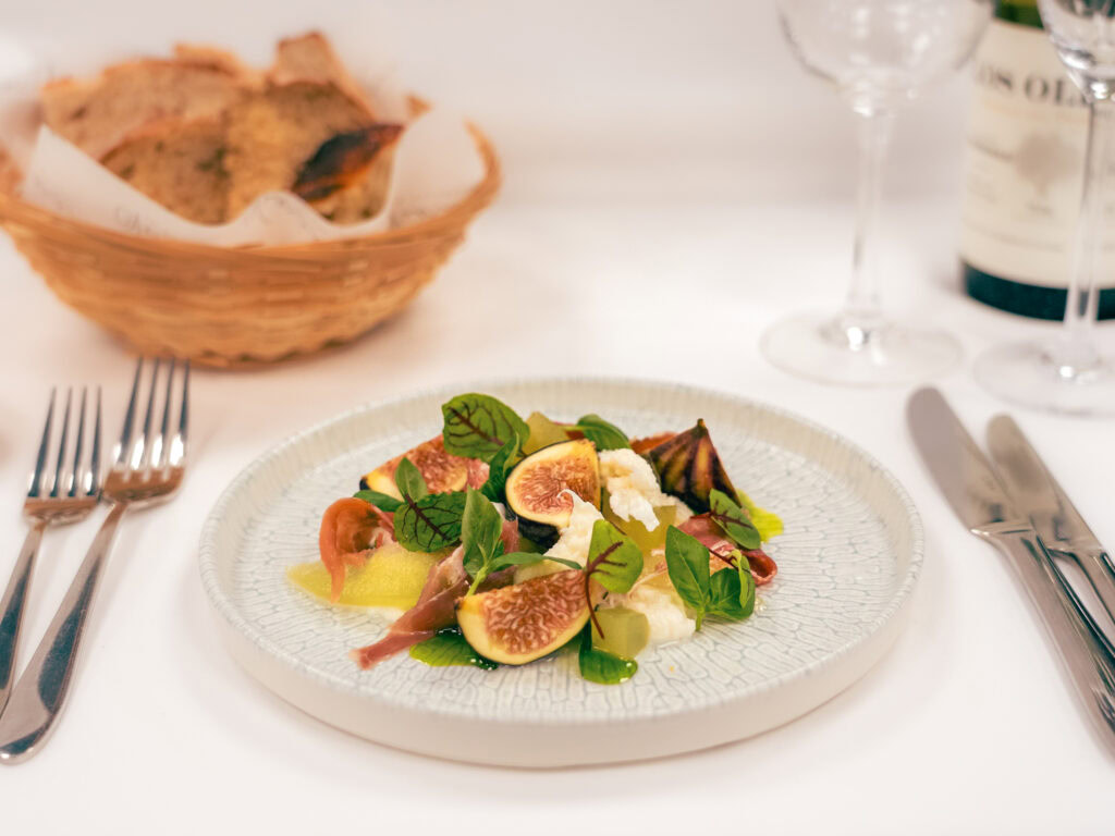 Fresh fig and goat cheese salad with greens and olive oil on a white plate at Vanilla In Allseasons, Cheshire.